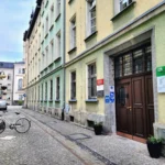 Narrow cobblestone street lined with pastel-colored buildings, a white bicycle at a bike rack, and a brown doorway.