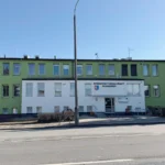 Public office building in Radom, Poland, with a white entrance and green side wings, showing the sign 'Powiatowy Urząd Pracy w Radomiu' above the door