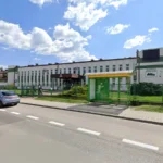 Public employment office building with white facade, green fence, and a yellow-roofed entrance on a sunny day.