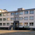 White multi-story office building with a central dark entrance and a sign reading "Powiatowy Urząd Pracy" by the ground-floor windows.