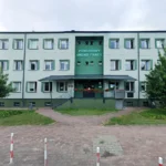 Public employment office building in Poland with a green center section and red flower boxes at the entrance