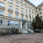 Facade of a beige, multi-story government building with a sign for Miejski Urząd Pracy at the entrance and a stone staircase.